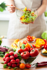 Beautiful young woman preparing delicious fresh vitamin salad. Concept of clean eating, healthy food, low calories meal, dieting, self caring lifestyle. Colorful vegetables, glass bowl. Close up