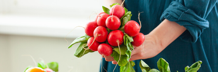 Beautiful young woman holding bouquet of fresh pink radish. Concept of clean eating, healthy food, low calories meal, vegetarian dieting, self caring lifestyle. Vegetables from market. Banner