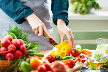 Beautiful young woman slicing yellow pepper, preparing delicious fresh vitamin salad. Concept of clean eating, healthy food, low calories meal, dieting, self caring lifestyle. Close up