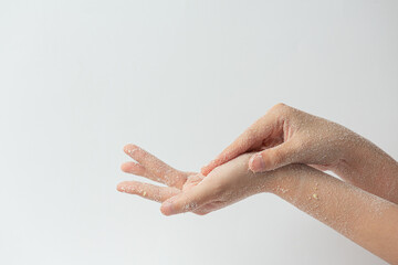 Young woman applying natural lemon scrub on hands against white background