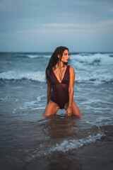 Fototapeta na wymiar Caucasian brunette in maroon swimsuit, on the beach enjoying the holidays in the sea water