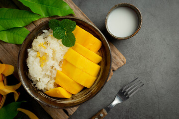 fresh ripe mango and sticky rice with coconut milk on dark background