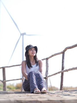 Asian woman relaxing outdoors looking happy and smiling with windmill as background