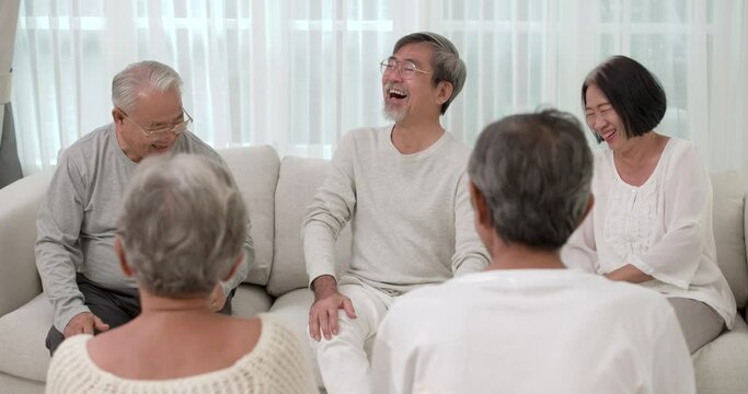 A Group of happy Asian seniors male and female sitting on sofa together and talking about funny story with a smile. The old man sharing his experience to his friend in common room at nursing home.
