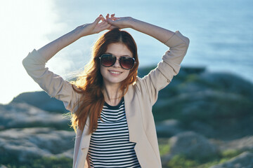 woman on vacation near the sea mountain gesturing with her hands above her head