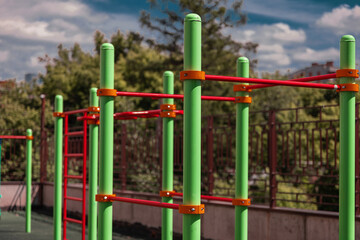 Fototapeta na wymiar green and red horizontal bars on a playground in the summer 