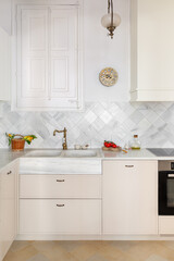 Interior of kitchen in rustic and vintage style. White furniture and marble tiles in bright cottage with fresh vegetables. Cozy atmosphere for cooking.