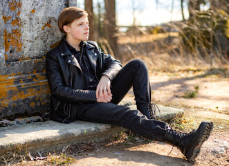 Informally dressed young guy sitting by a marble monument