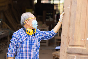 Elder worker wood woodcraft retire hobby for good retirement, Asian male mature professional master of making wooden furniture with face mask protective.