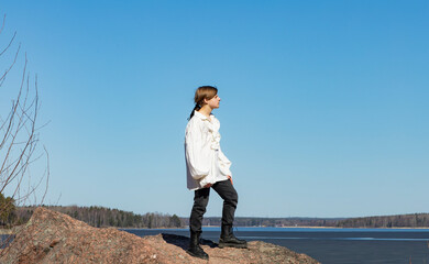 Boy standing on a granite rock against a background of blue sky and water