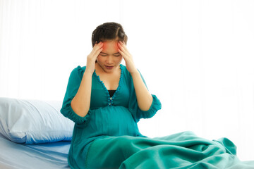 Asian pregnant women sitting with migraine headaches in the patient's bed, dizziness, headaches :...