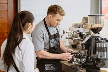 Professional Barista working in the cafe teaching make a coffee with espresso machine to new young...