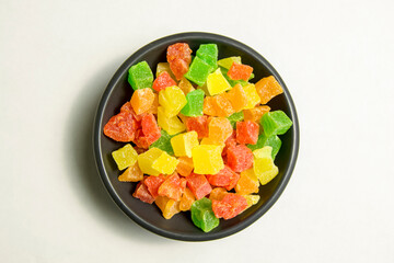pieces of dried fruit on a black plate. candied fruits close-up in a plate on a light background