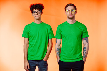 two friends with glasses in green t-shirts are standing next to fashion