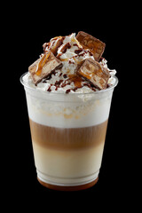 Iced coffee with whipped cream, ice cream and topping in a cardboard glass, black background, isolate