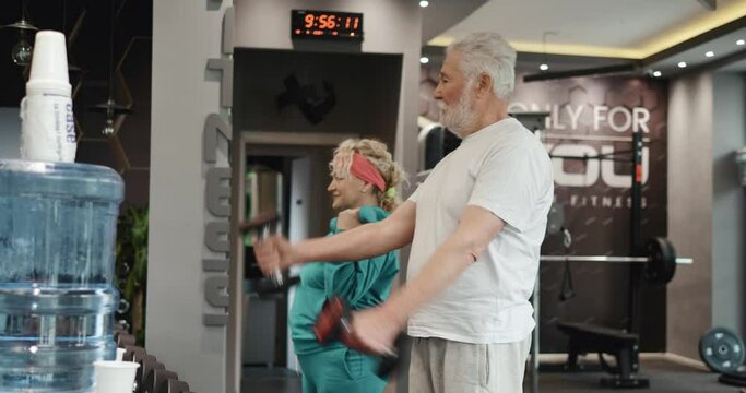 Couple of seniors training with dumbbells in the gym