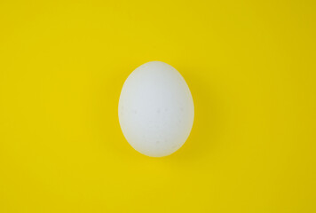 White egg on the yellow background. Copy space. Minimalism, original and creative photo. Beautiful wallpaper. Easter holidays.