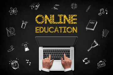 Online education concept, hands working laptop with online education concept chalk text on chalkboard