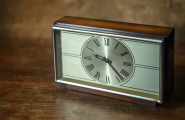 An old mechanical mahogany clock sits on a wooden table