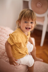 Fototapeta premium Small happy little boy playing in bedroom.