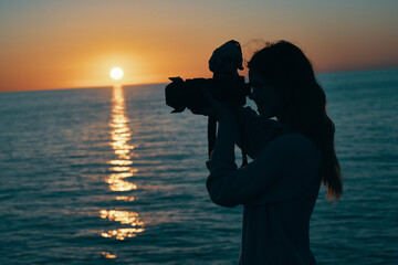 Obraz premium photographer with a camera at sunset near the sea