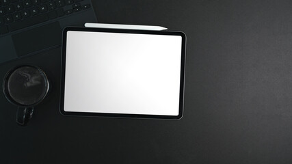 Top view of digital tablet with white screen, coffee cup and stylus pen on black leather.