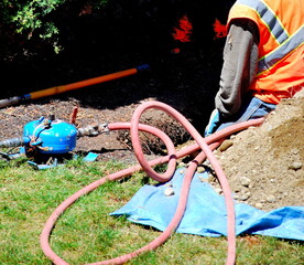 Man repairing underground water pipe outdoors.