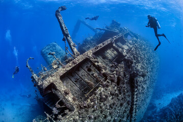 Divers exploring the outside of a shipwreck