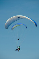 Two paragliders flying in a blue sky