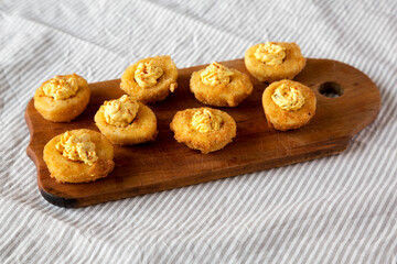 Homemade Deep-fried Deviled Eggs with Paprika on a rustic wooden board, side view.