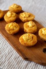 Homemade Deep-fried Deviled Eggs with Paprika on a rustic wooden board, low angle view.