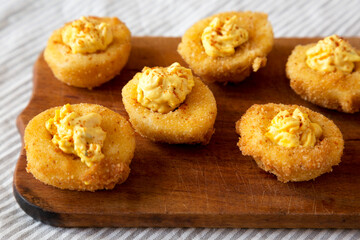 Homemade Deep-fried Deviled Eggs with Paprika on a rustic wooden board, side view. Close-up.