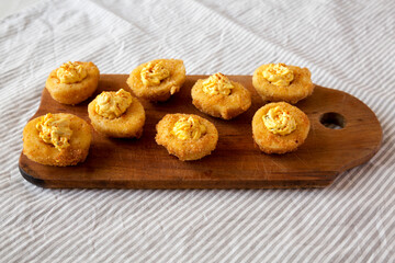 Homemade Deep-fried Deviled Eggs with Paprika on a rustic wooden board, low angle view.