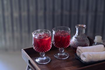 Welcome drink red mocktail and white towel served on wooden tray.
