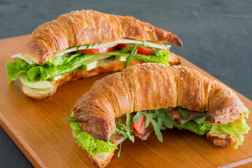 Crispy croissant with salmon, lettuce and cucumbers. Tasty breakfast