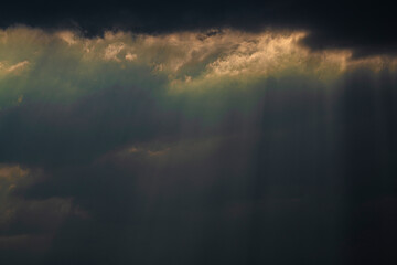 Dark sky with clouds, through which the rays of the sun break through