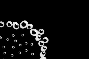 A circle of toy eyes. filled with small eyes on a black background