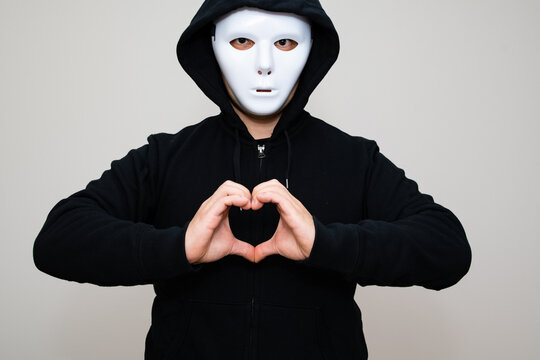 Hacker with anonymous mask making gesture of heart