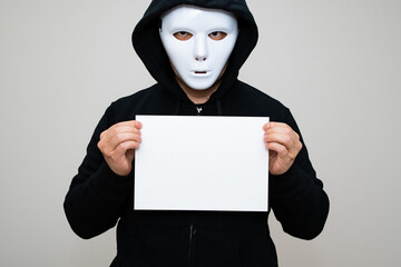 Hacker with anonymous mask holding a piece of white paper