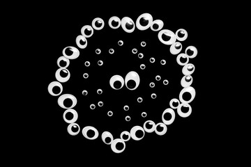 A circle of toy eyes. filled with small eyes on a black background