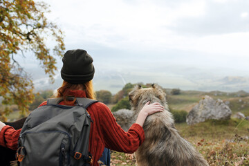 woman tourist hugs a dog in nature admires the landscape
