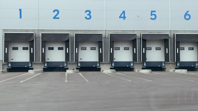Exterior of large distribution warehouse with gates for trucks, logistic, storage, shipment, transportation. High quality 4k footage