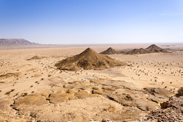 A desert landscape viewed from the Natural Arch of Riyadh. A plain surrounded by the mountain ridge - a Martian-like landscape.