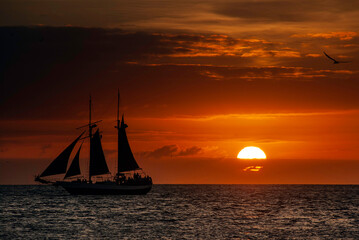 Silhouette of a sailing boat in full sail at sunset