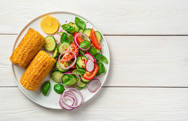 Salad with fresh vegetables: tomato, cucumber and radish, seasoned with sesame seeds and spices on a white wooden table with space for copying.