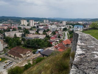 Fototapeta premium View of the town of Doboj and the hilly countryside from the Gradina fortress on the hill above the town during a cloudy summer day