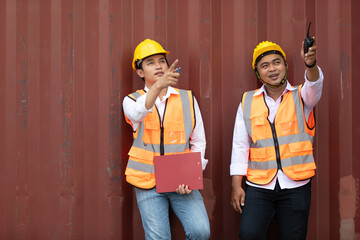 two factory workers or engineers looking and pointing something in containers warehouse storage