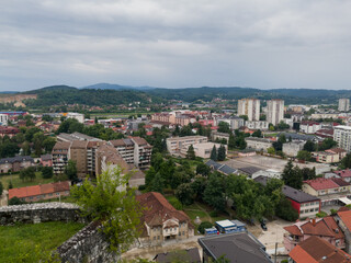 Obraz premium View of the town of Doboj and the hilly countryside from the Gradina fortress on the hill above the town during a cloudy summer day
