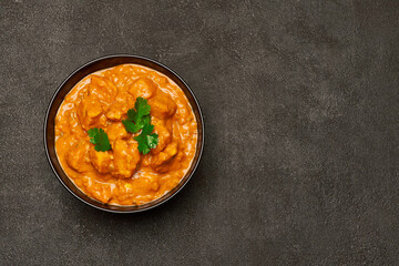 Black ceramic bowl of Traditional Chicken Curry on dark concrete background