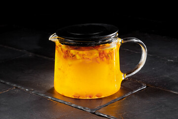 Sea buckthorn tea in a teapot on a gray background